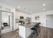 Thumbnail 8 of 59 - a kitchen with an island and bar stools in a living room at The Quarry Luxury Apartment Homes, Colorado, 80526