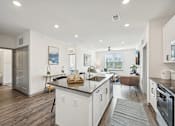 Thumbnail 5 of 59 - a kitchen with an island and a living room with a couch at The Quarry Luxury Apartment Homes, Fort Collins, 80526