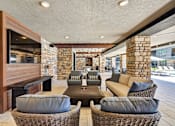Thumbnail 9 of 32 - A modern outdoor seating area with a stone wall and wicker furniture.at Refinery at Pointe17 Apartments, Phoenix, AZ, 85085