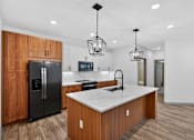 Thumbnail 26 of 32 - A modern kitchen with wooden cabinets and a black refrigerator.at Refinery at Pointe17 Apartments, Phoenix, AZ, 85085