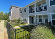 Thumbnail 33 of 56 - an apartment building with a grassy yard and a black fence at Watermark at Steele Crossing, Arkansas, 72703