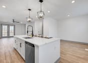 Thumbnail 39 of 58 - a large white kitchen with a large island and two hanging lights at Meridian at CityPlace, Woodbury Minnesota
