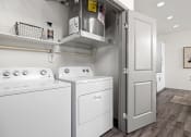 Thumbnail 9 of 88 - a white washer and dryer in a room with a refrigerator and a door at The Depot in The Depot Raymore, MO 64083