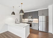 Thumbnail 18 of 39 - A modern kitchen with a white island and stainless steel appliances.