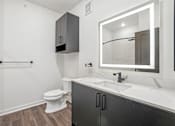 Thumbnail 20 of 39 - A bathroom with a toilet, sink, and mirror.