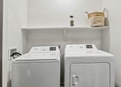 Thumbnail 14 of 20 - A white washing machine and dryer in a small laundry room.