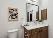 Thumbnail 12 of 20 - A bathroom with a toilet, sink, and a mirror.