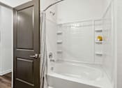 Thumbnail 13 of 20 - A white bathroom with a white tub and a white shower.