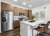 Thumbnail 6 of 20 - A modern kitchen with a stainless steel refrigerator and a white countertop.