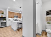 Thumbnail 35 of 58 - a white bathroom with a white toilet and a kitchen with wood floors at Meridian at CityPlace, Woodbury, 55125
