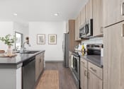 Thumbnail 10 of 58 - a modern kitchen with stainless steel appliances and wooden cabinets at Palm Grove in Ellenton, FL 34222