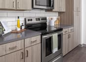Thumbnail 12 of 58 - a kitchen with stainless steel appliances and wooden cabinets at Palm Grove in Ellenton, FL 34222