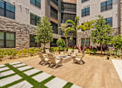Thumbnail 16 of 60 - A patio with a table and chairs in front of a building.