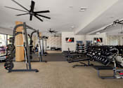 Thumbnail 17 of 60 - A well-equipped gym with a variety of exercise machines and a ceiling fan.