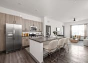 Thumbnail 26 of 60 - A modern kitchen with a refrigerator, microwave, oven, and sink.