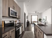 Thumbnail 27 of 60 - A modern kitchen with dark countertops and wooden cabinets.