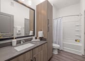 Thumbnail 28 of 60 - A modern bathroom with a sink, mirror, toilet, and bathtub.