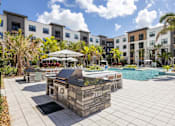 Thumbnail 43 of 60 - A pool area with a stone structure in the middle of a paved area.