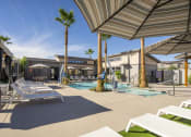 Thumbnail 41 of 68 - a pool with lounge chairs and umbrellas next to a building at Grandstone at Sunrise, Peoria, AZ