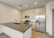 Thumbnail 34 of 46 - a kitchen with a large island and stainless steel refrigerator at Alta25, Monument, Colorado