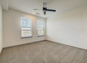 Thumbnail 40 of 46 - an empty living room with a ceiling fan and two windows at Alta25, Monument, Colorado