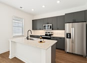 Thumbnail 2 of 54 - A modern kitchen with a white island and stainless steel appliances.