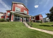 Thumbnail 50 of 56 - a row of red houses on a hill with green grass at Watermark at Steele Crossing, Arkansas, 72703