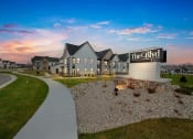 Thumbnail 6 of 45 - an exterior view of the residences at dusk with a sidewalk and grass at The BLVD at Wilson Crossings, Wyoming, MI 49418