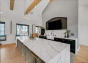 Thumbnail 37 of 45 - the kitchen has a large island with marble counter tops and a large tv at The BLVD at Wilson Crossings, Wyoming, 49418