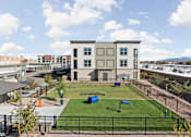Thumbnail 9 of 108 - a park with grass and a playground in front of a building at The Maddox Luxury Apartment Homes, Buckeye, AZ, 85326