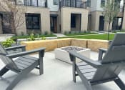 Thumbnail 52 of 58 - a patio with two chairs and a planter in front of a building at Meridian at CityPlace in Woodbury, MN 55125