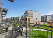 Thumbnail 15 of 58 - a balcony with a table and chairs overlooking a yard and apartment buildings at Meridian at CityPlace, Woodbury, MN