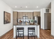 Thumbnail 30 of 40 - a kitchen with a large island with two stools and a stainless steel refrigerator  at Stella Luxury Apartment Homes, San Tan Valley, AZ, 85143