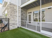 Thumbnail 8 of 49 - a patio with grass and a stone wall on the side of a house at Drift, Daytona Beach, FL, 32117