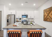 Thumbnail 10 of 56 - an open kitchen with an island with three chairs and a stainless steel refrigerator and microwave at Notch66, Longmont, Colorado