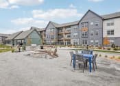 Thumbnail 33 of 56 - a patio with a table and chairs in front of an apartment building at Notch66, Longmont, Colorado