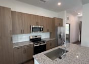Thumbnail 2 of 17 - A kitchen with wooden cabinets and a granite countertop.