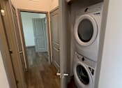Thumbnail 11 of 17 - A washing machine is in a small room with a door open.