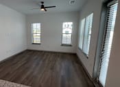 Thumbnail 13 of 17 - A room with a ceiling fan and wooden flooring.