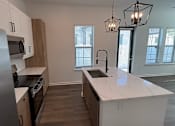 Thumbnail 17 of 17 - A kitchen with a white countertop and wooden cabinets.
