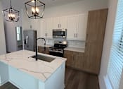 Thumbnail 5 of 17 - A kitchen with a white island and wooden cabinets.