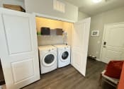 Thumbnail 46 of 56 - a laundry room with a washer and dryer and a shelf over the door at Watermark at Steele Crossing, Fayetteville, AR