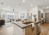 Thumbnail 81 of 88 - a kitchen with an island and a living room with a couch at The Depot in The Depot Raymore, MO 64083