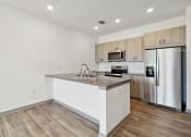 Thumbnail 69 of 88 - a kitchen with a large island and a stainless steel refrigerator at The Depot in The Depot Raymore, MO 64083