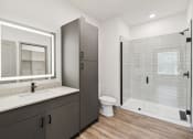 Thumbnail 11 of 88 - a bathroom with a shower and a sink and a toilet at The Depot in The Depot Raymore, MO 64083