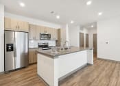 Thumbnail 80 of 88 - a kitchen with a large island and a stainless steel refrigerator at The Depot in The Depot Raymore, MO 64083