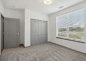 Thumbnail 71 of 88 - the living room of an apartment with a large window and gray doors at The Depot in The Depot Raymore, MO 64083