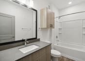 Thumbnail 82 of 88 - a bathroom with a mirror and a sink and a shower at The Depot in The Depot Raymore, MO 64083