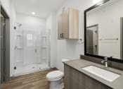 Thumbnail 76 of 88 - a bathroom with a toilet sink and mirror and a shower at The Depot in The Depot Raymore, MO 64083