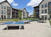 Thumbnail 4 of 88 - two ping pong tables in a courtyard with apartments in the background at The Depot Raymore, MO 64083